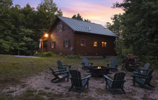 Log cabin exterior with fire pit at dusk